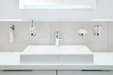 Weißes Waschbecken mit Chrom-Armatur und Wandhaltern für Badzubehör