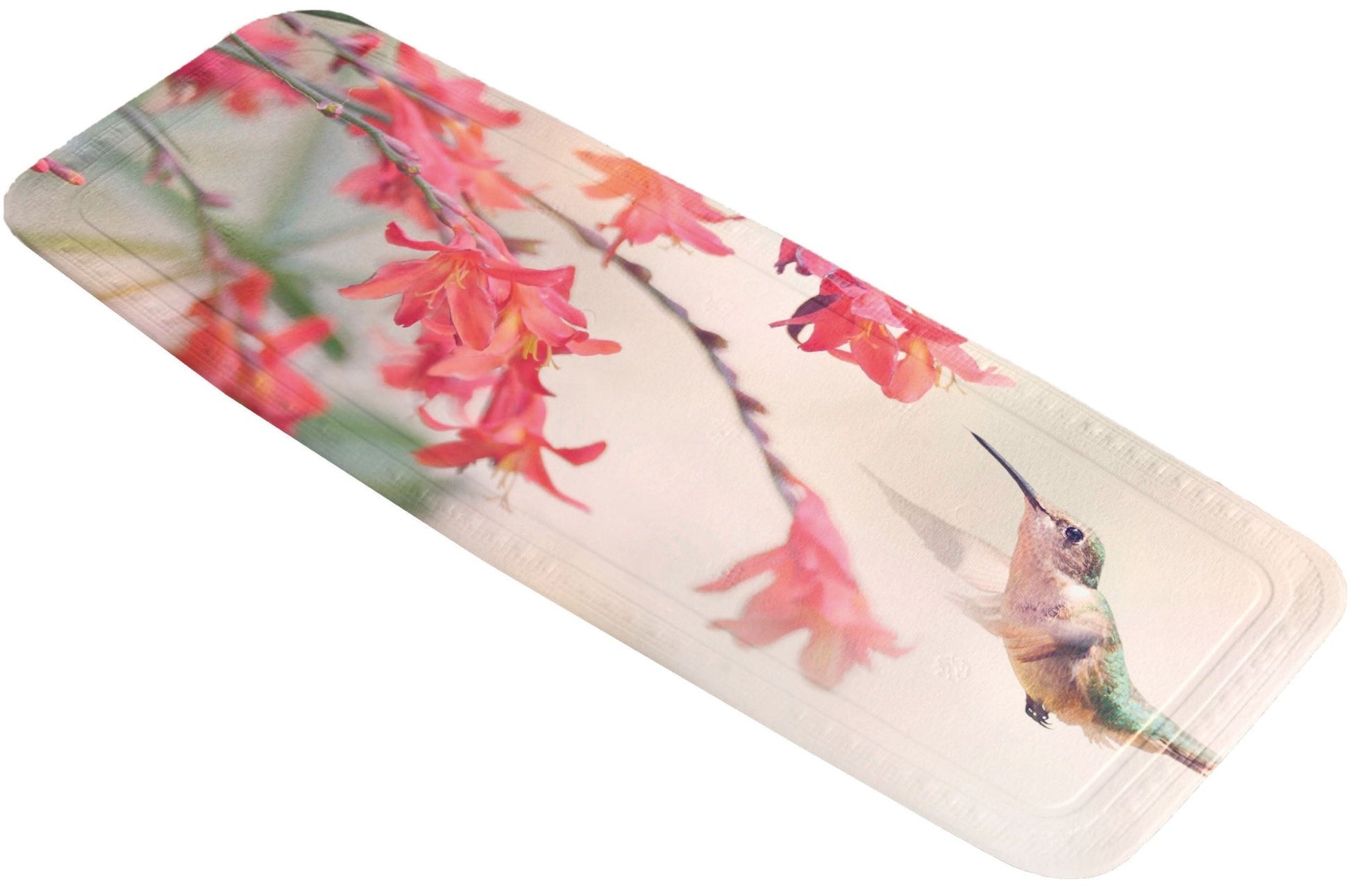 Wanneneinlage KOLIBRI Multicolor mit Kolibri und rosa Blüten liegt schräg vor weißem Hintergrund.