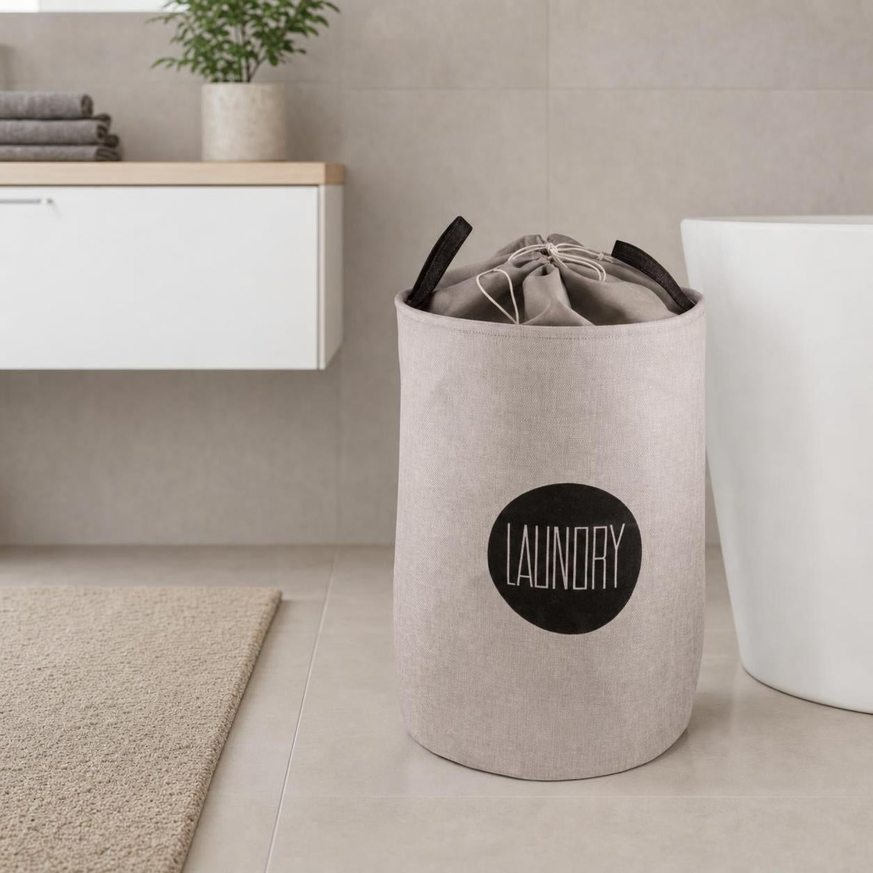 Ein beiger Wäschekorb mit Zugbeutel steht im modernen Badezimmer.