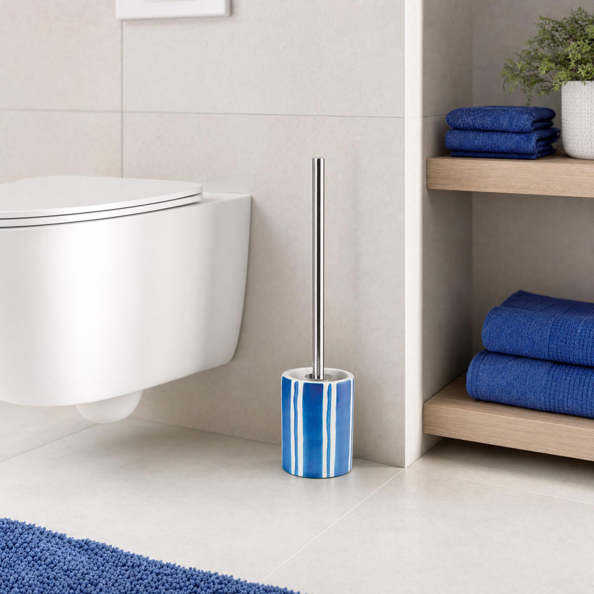 Blau-weiße WC-Bürste neben Wand-WC im modernen Bad mit blauen Handtüchern.