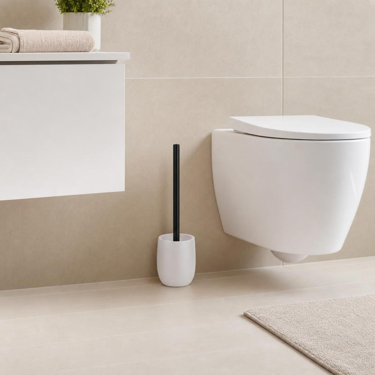 Weiße WC-Bürste mit schwarzem Griff steht neben der Toilette im Bad.