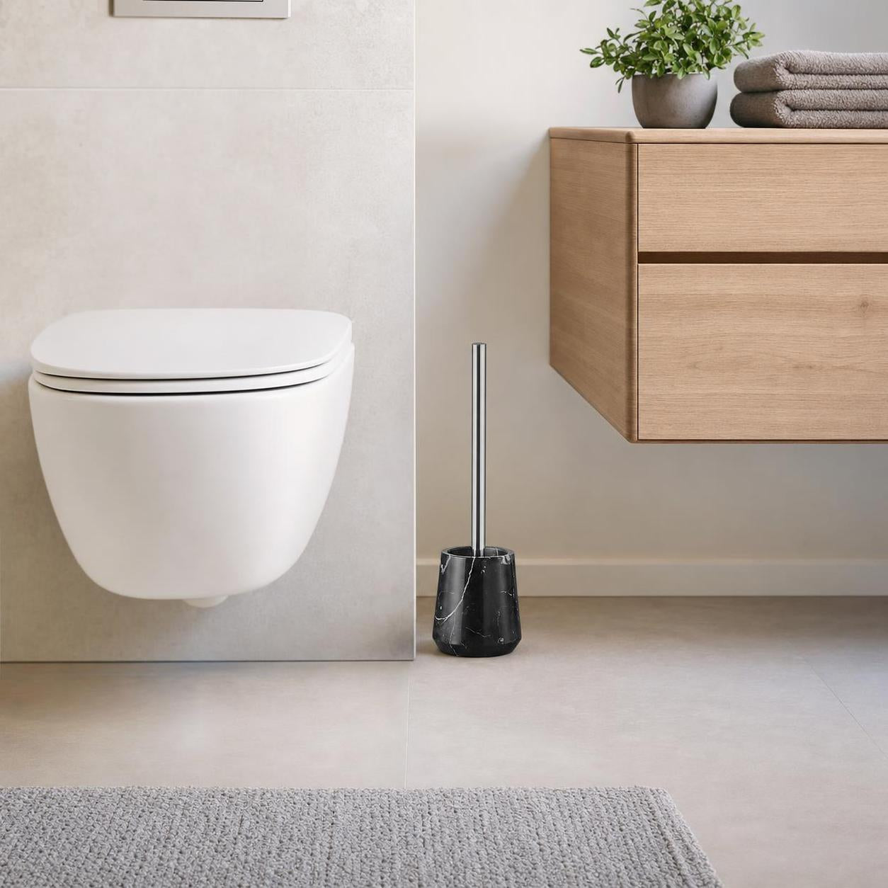 Schwarze WC-Bürste im Marmorhalter steht neben Toilette und Holzschrank.