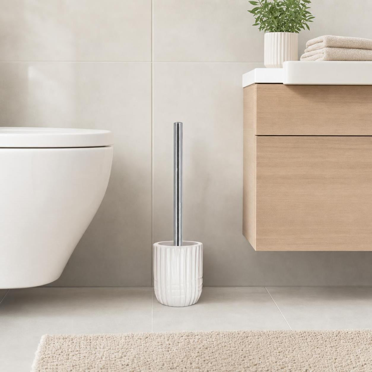 Eine weiße WC-Bürste mit Halter steht neben Toilette und Waschtisch.