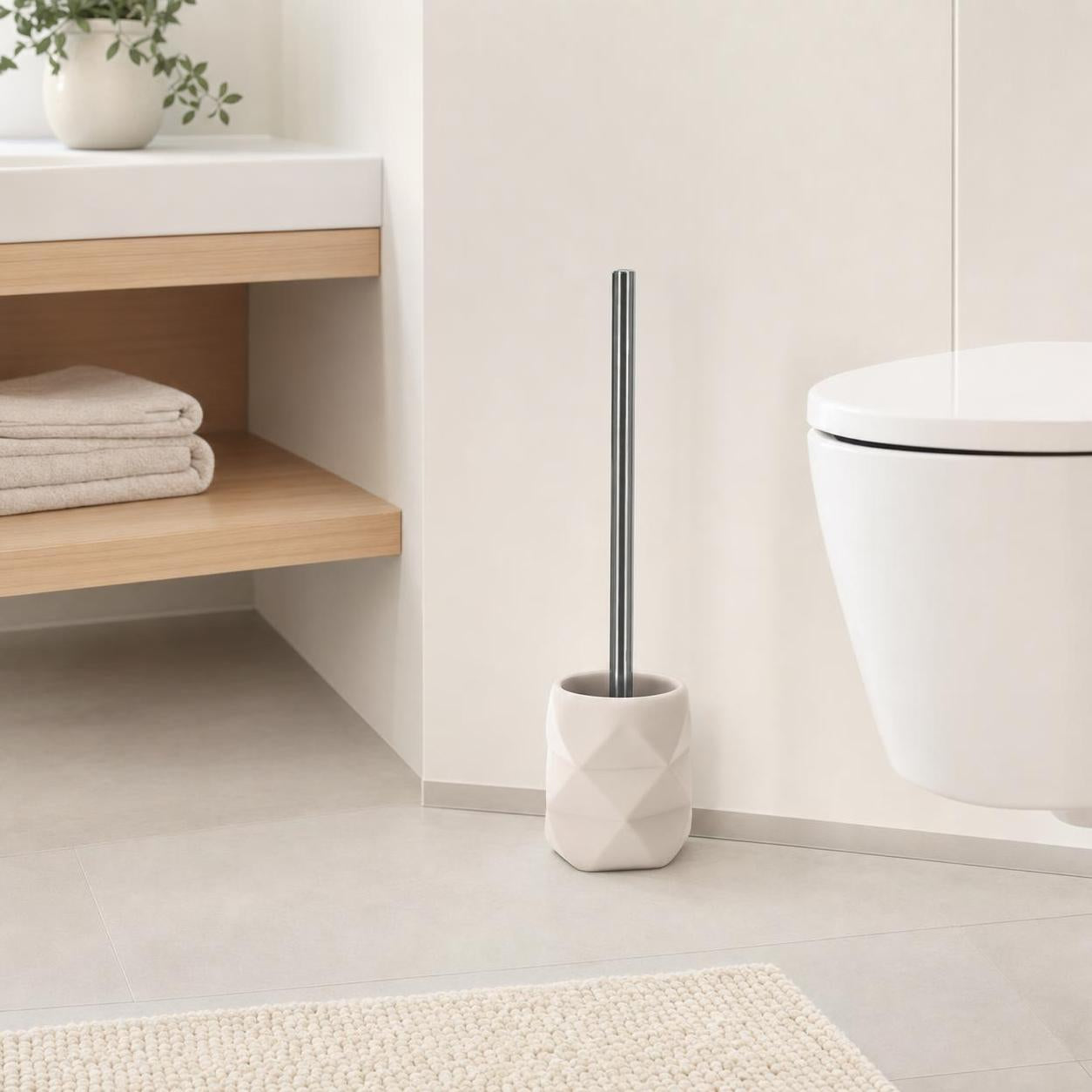 Weiße WC-Bürste mit facettiertem Halter steht neben der Toilette.