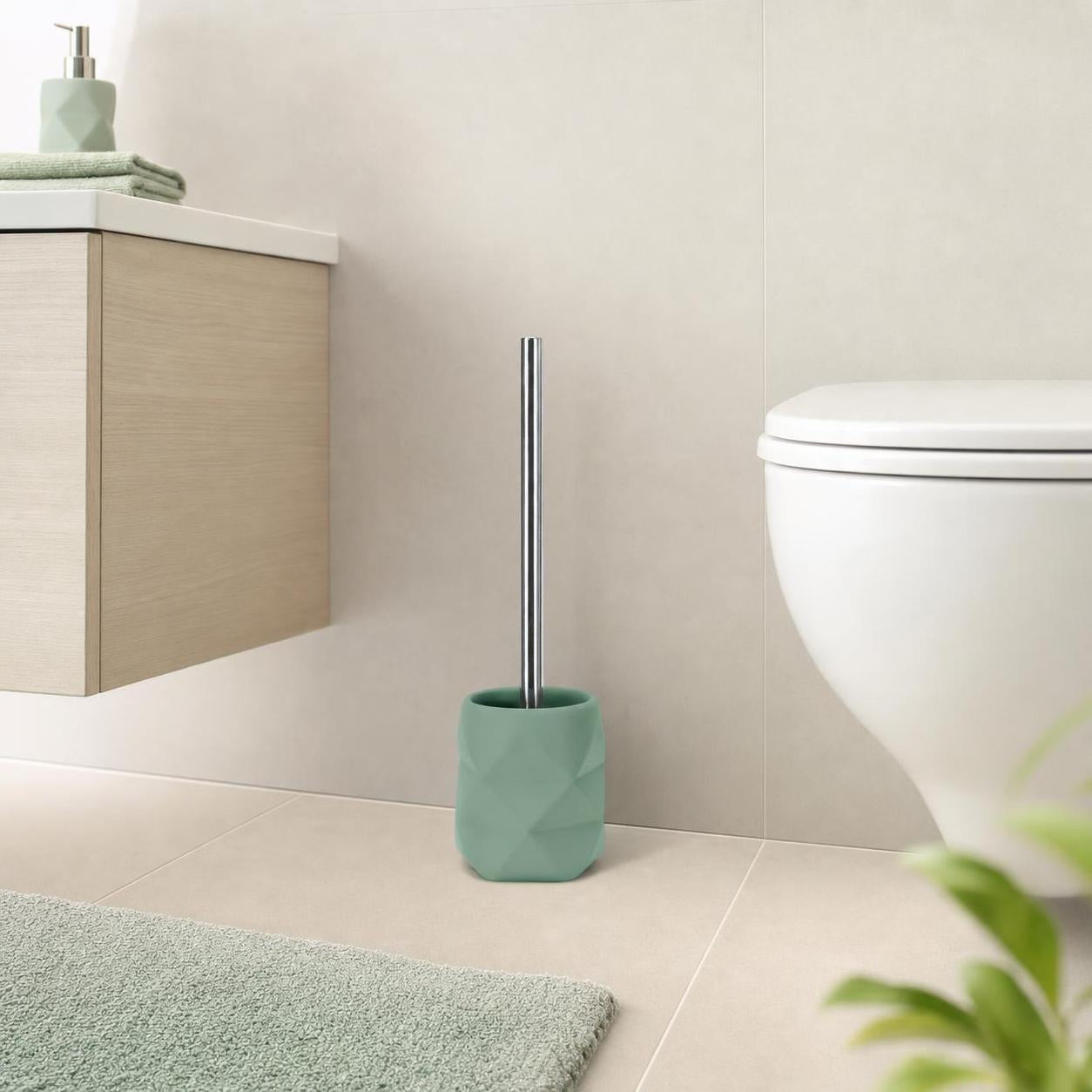 Mintgrüne WC-Bürste mit Facettenbehälter steht neben der Toilette.