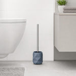 Eine blaue WC-Bürste mit Halter steht neben der Toilette im Bad.