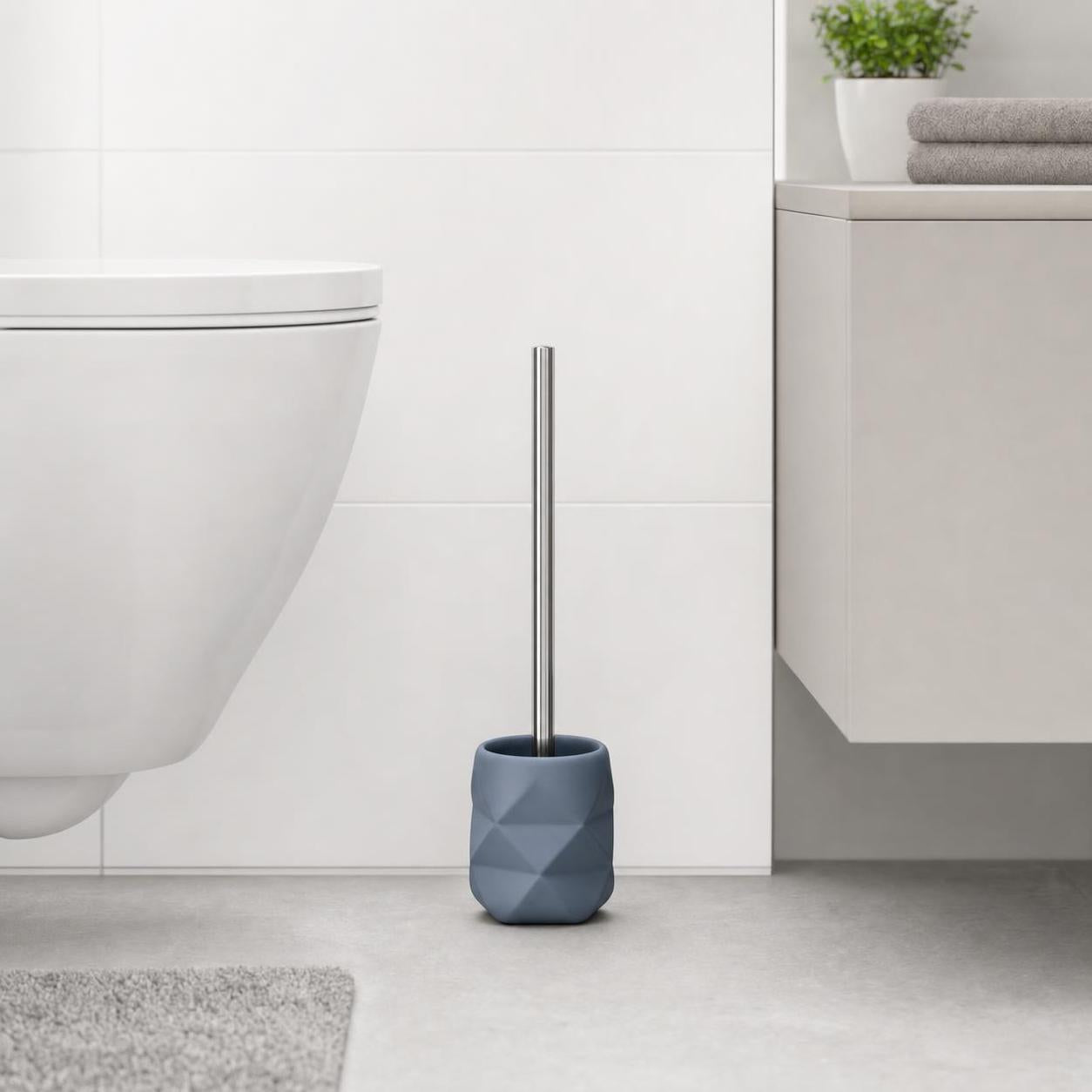 Eine blaue WC-Bürste mit Halter steht neben der Toilette im Bad.