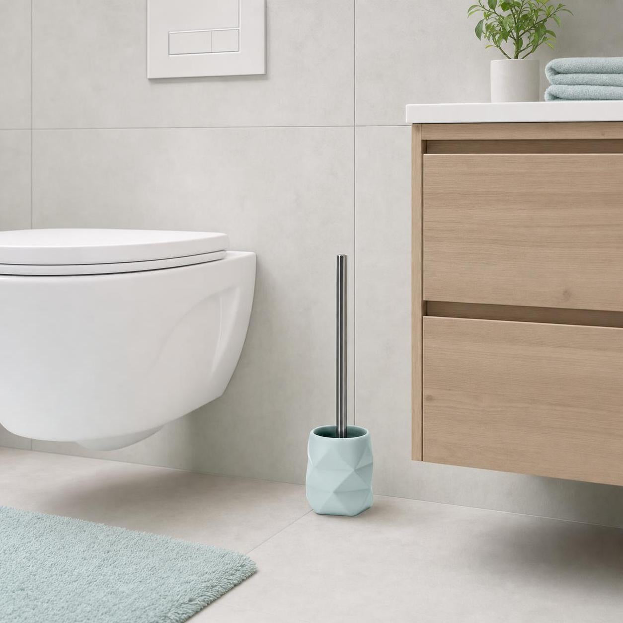 Hellblaue WC-Bürste steht neben Toilette und Holzwaschtisch im Bad.