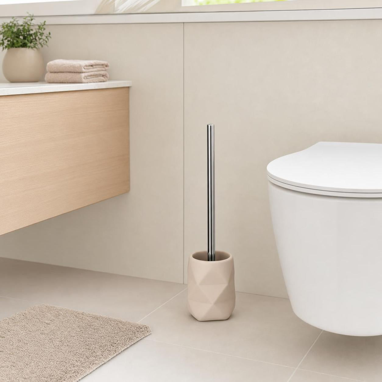 Eine WC-Bürste im beigen Halter steht neben der Toilette im Bad.