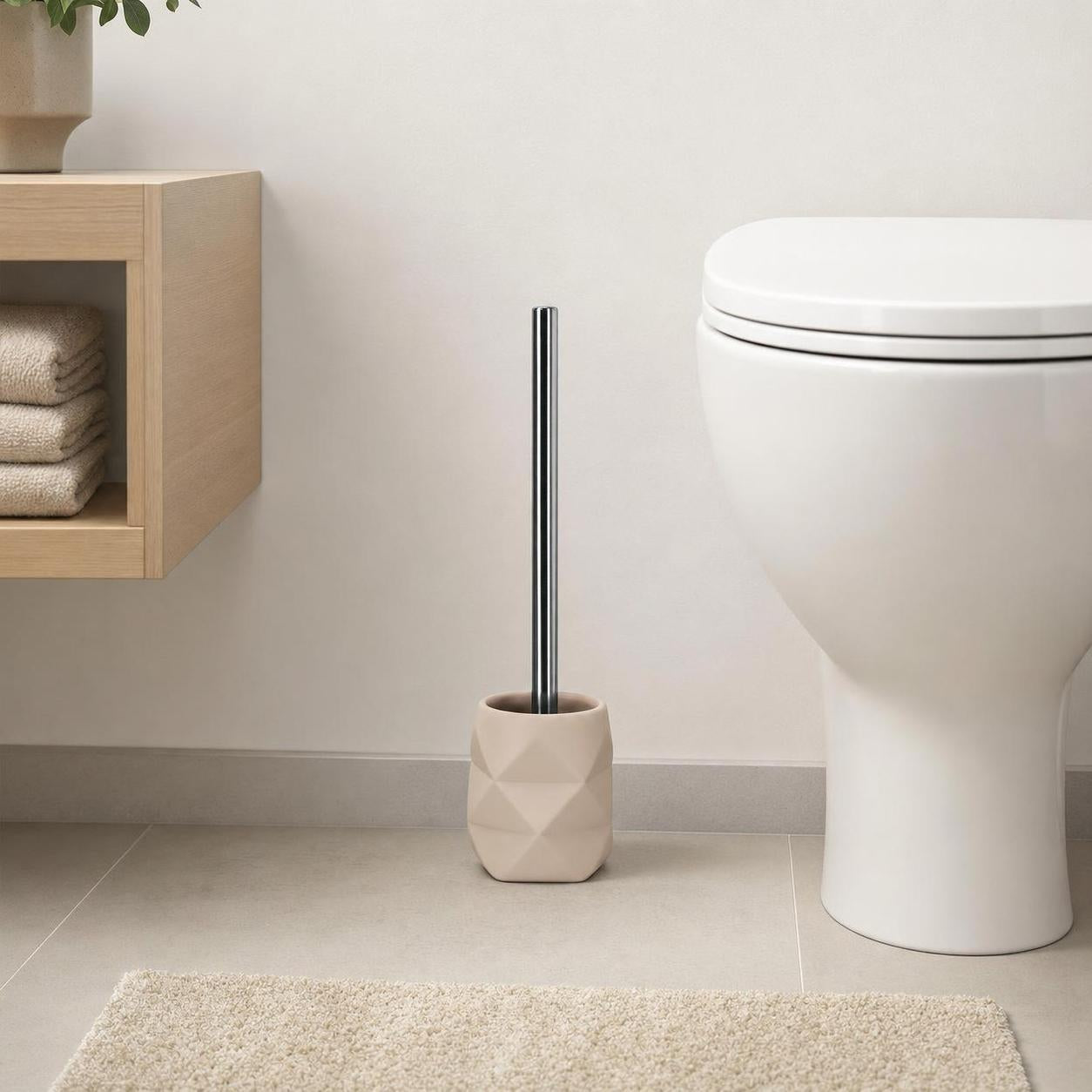 Beige WC-Bürste mit Chromgriff steht neben einer weißen Toilette.