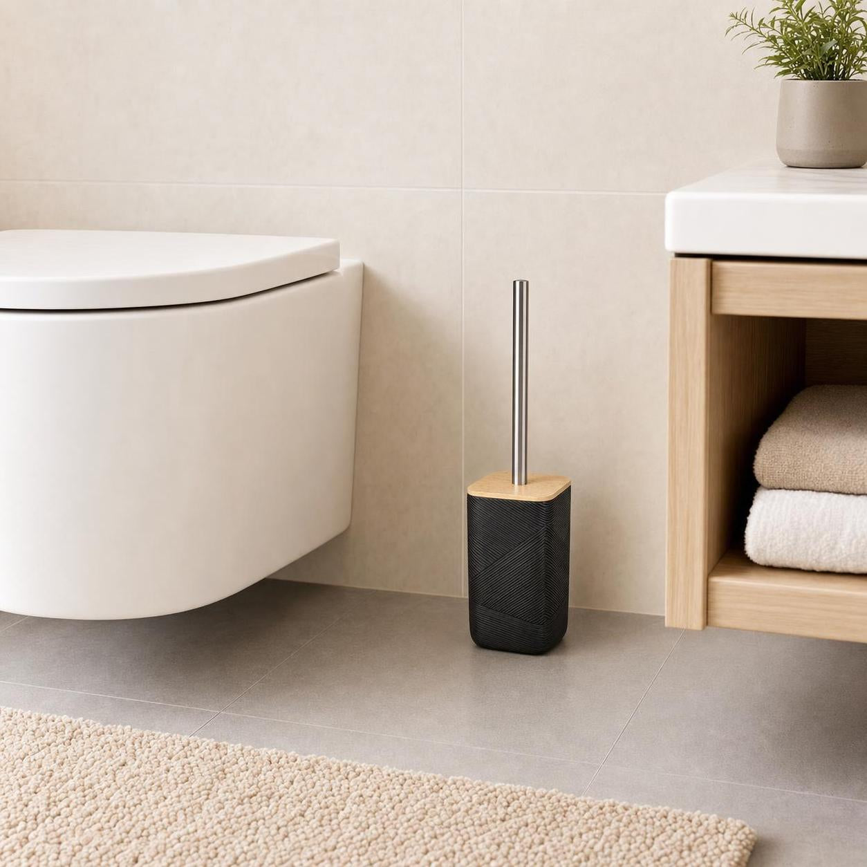 Eine schwarze WC-Bürste mit Holzdeckel steht neben der Toilette.