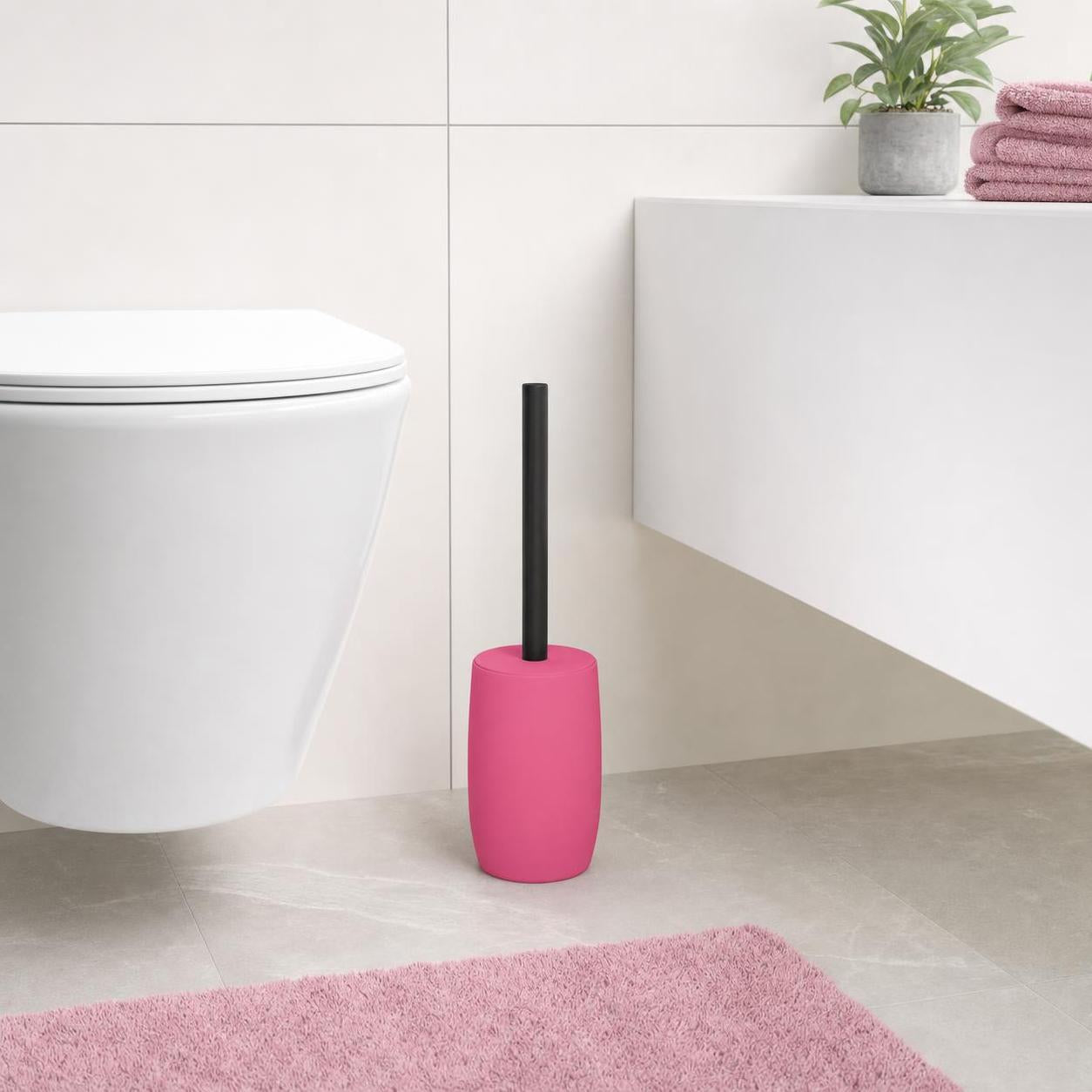 Eine pinke WC-Bürste mit schwarzem Griff steht neben der Toilette.