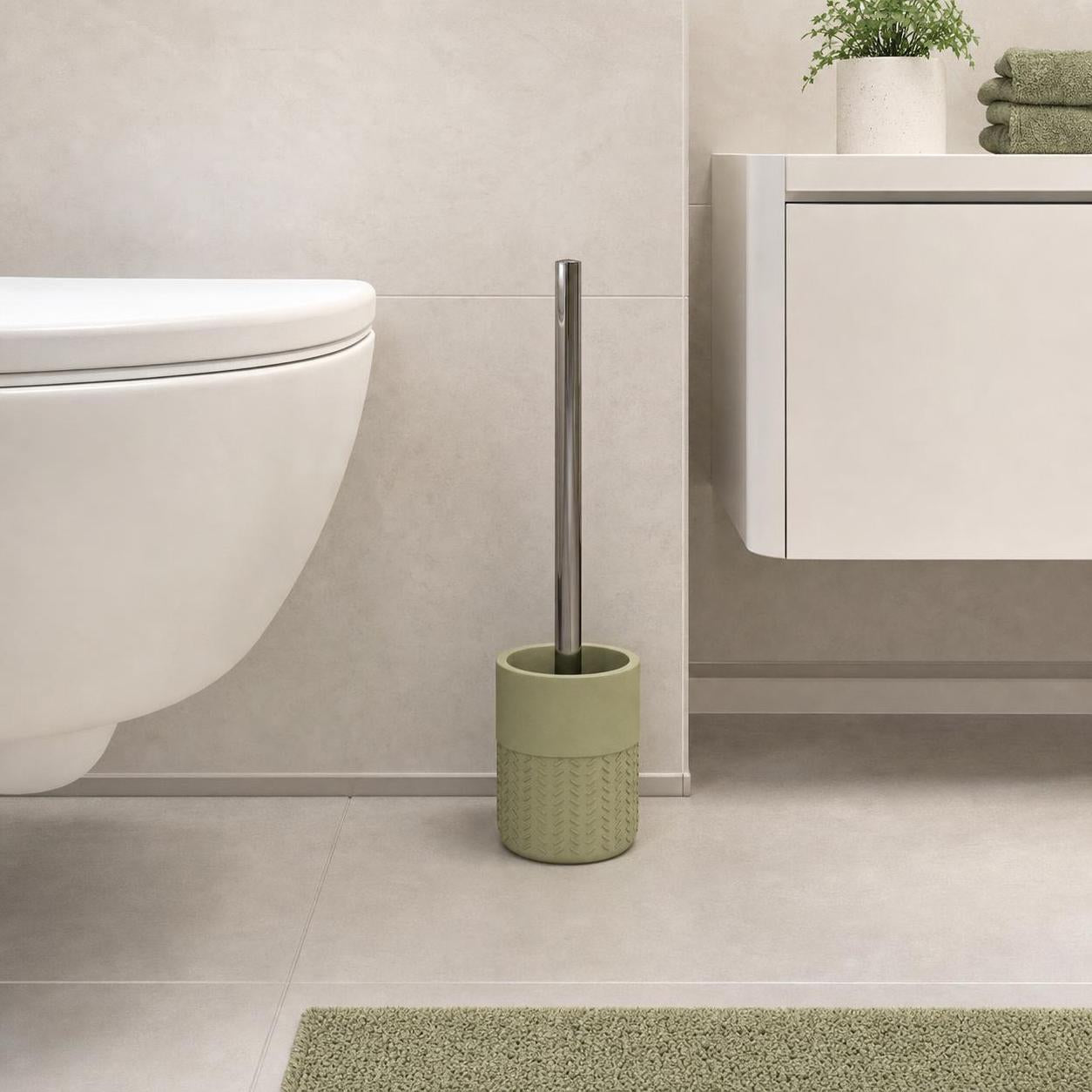 Eine grüne WC-Bürstengarnitur steht neben der Toilette im Bad.