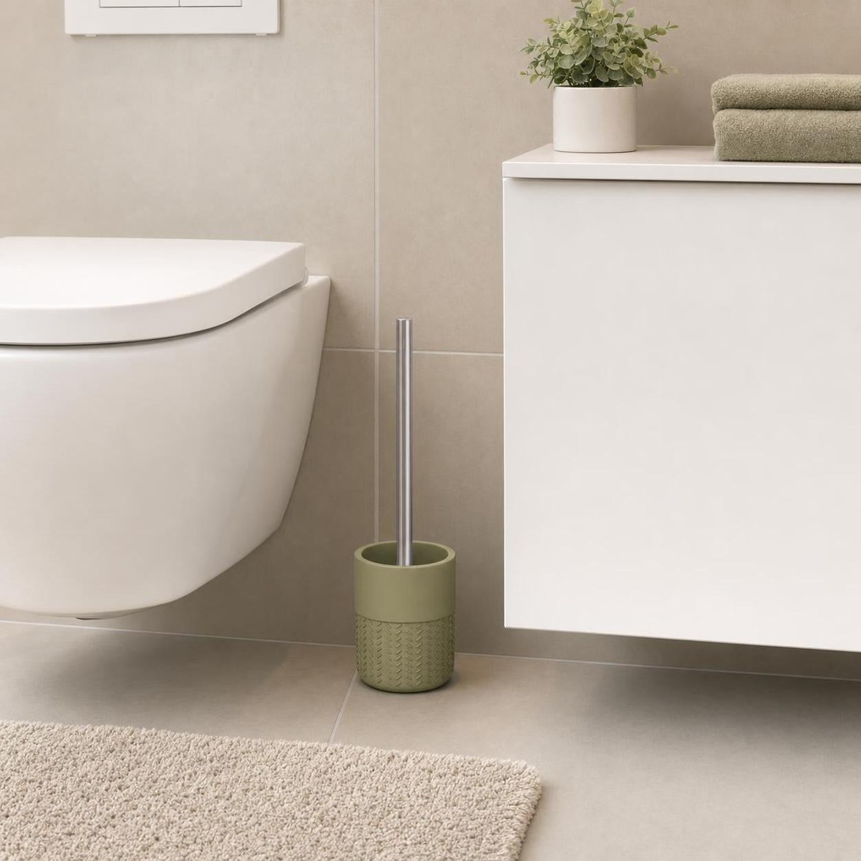 Eine olivgrüne WC-Bürste steht neben Toilette und Badschrank.