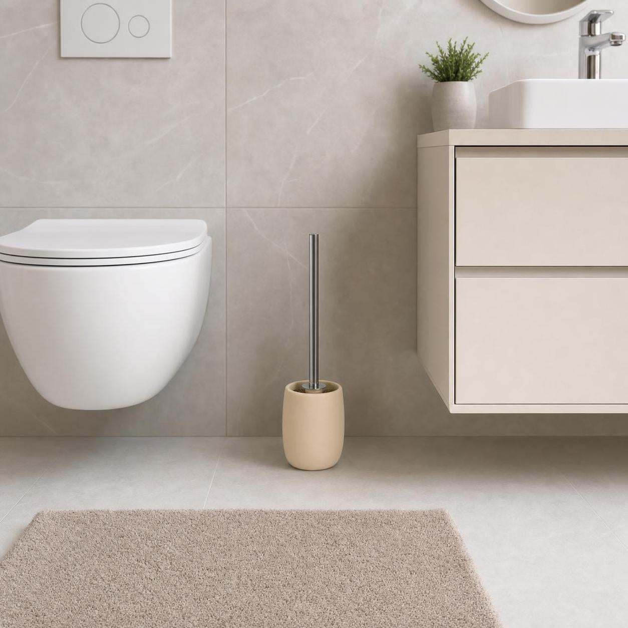 Eine beige WC-Bürste steht zwischen Toilette und Waschtisch im Bad.