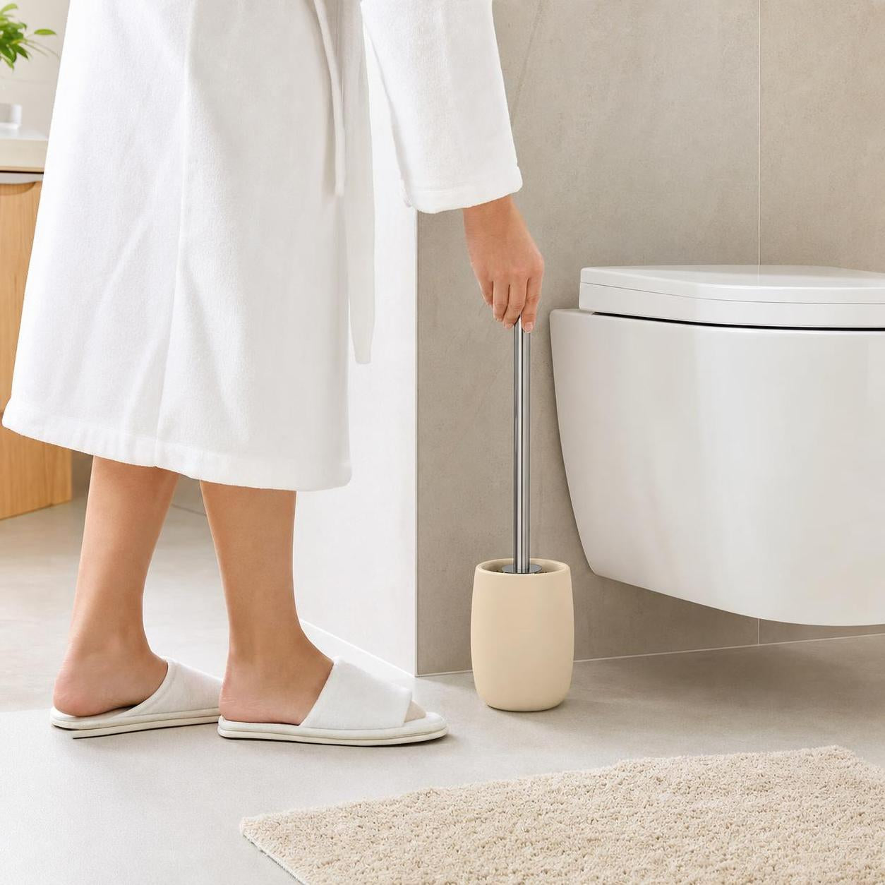 Eine Person greift im Bad zur Toilettenbürste im beigen Halter.