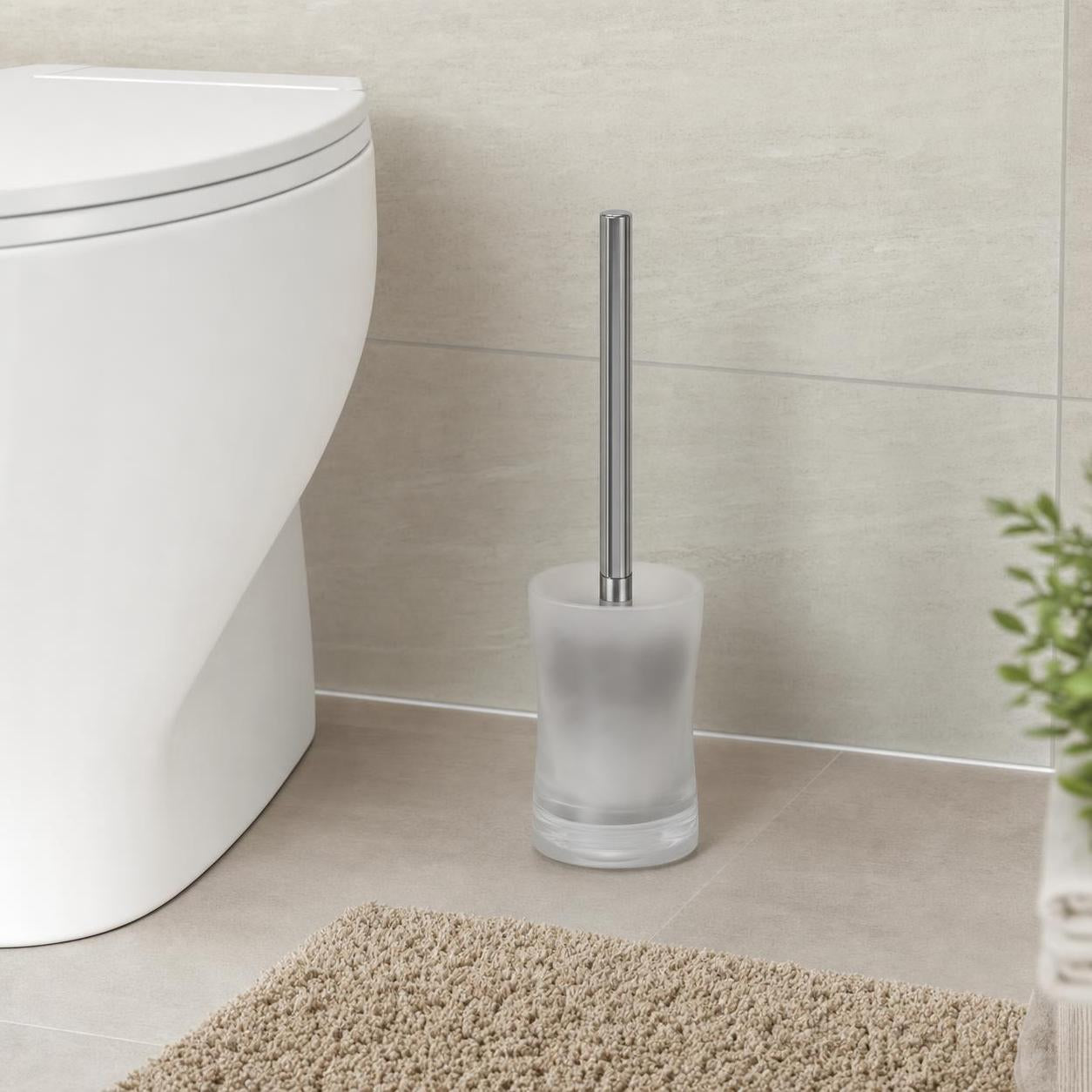 Eine WC-Bürste mit Milchglasbehälter steht neben der Toilette.