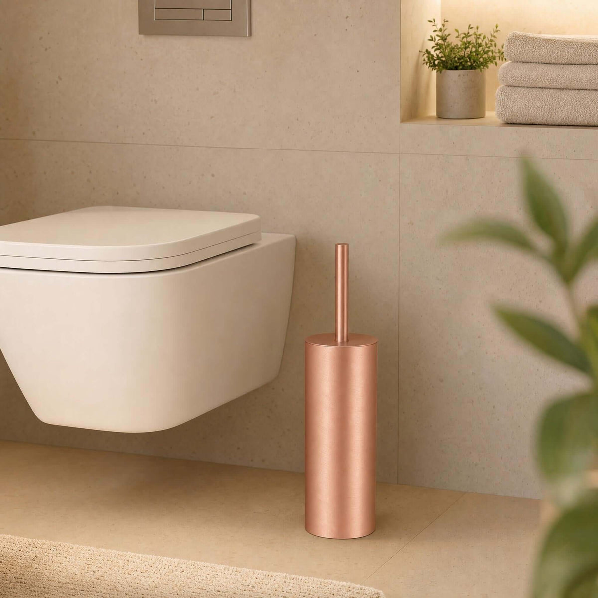 Kupferfarbene WC-Bürste neben wandhängendem WC im modernen Bad.