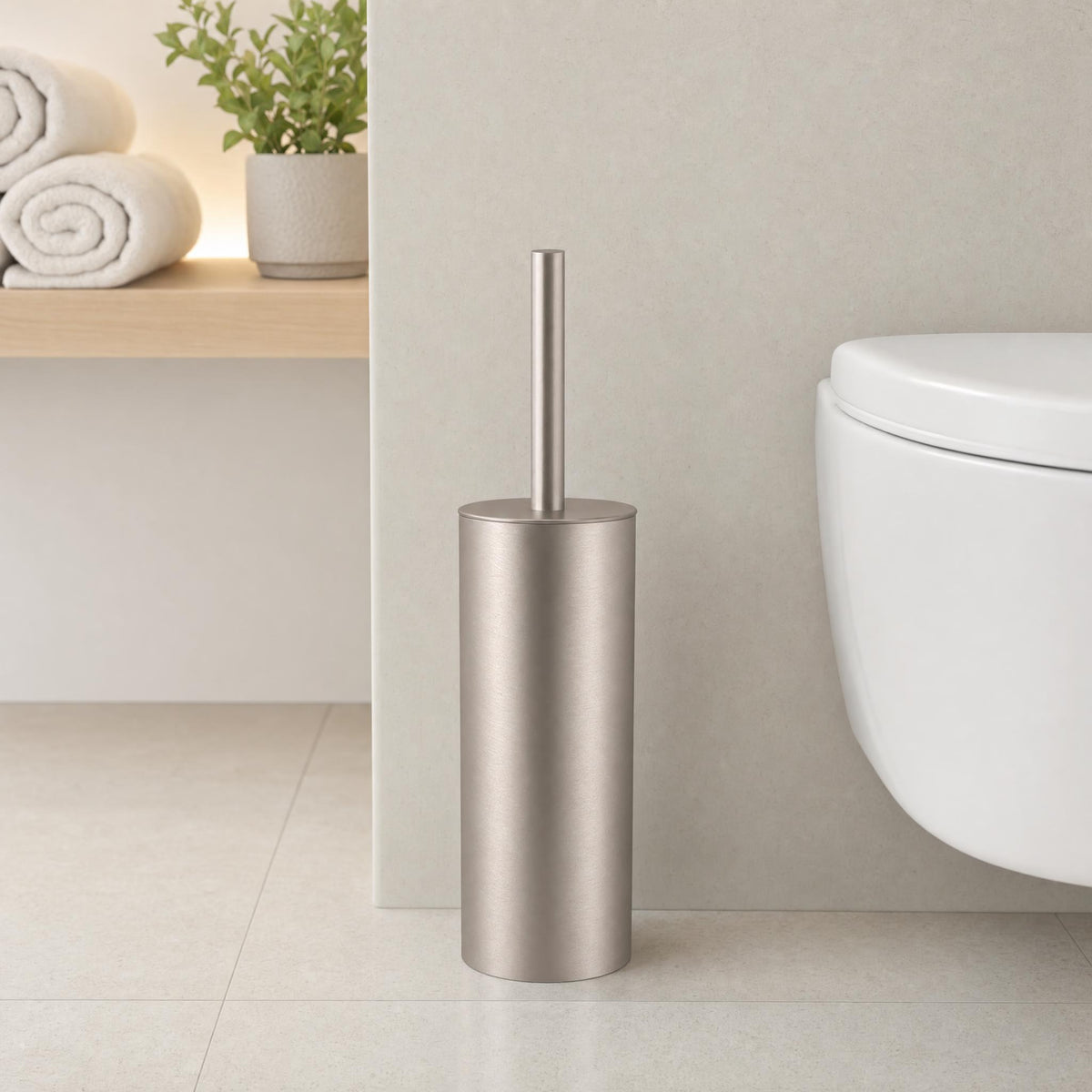 Silberfarbene WC-Bürste neben modernem Hänge-WC im hellen Badezimmer.