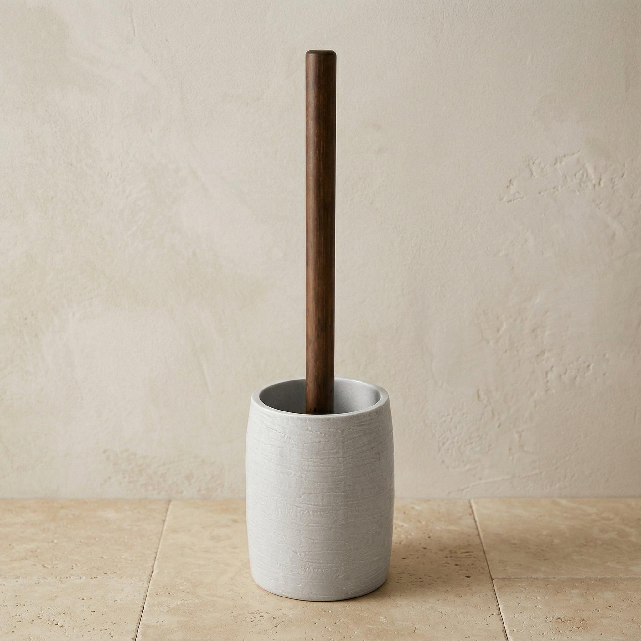 Toilettenbürste mit Holzgriff in heller Keramikhalterung auf Fliese