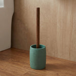 Toilettenbürste mit Holzstiel in grünem Halter auf Holzboden im Bad