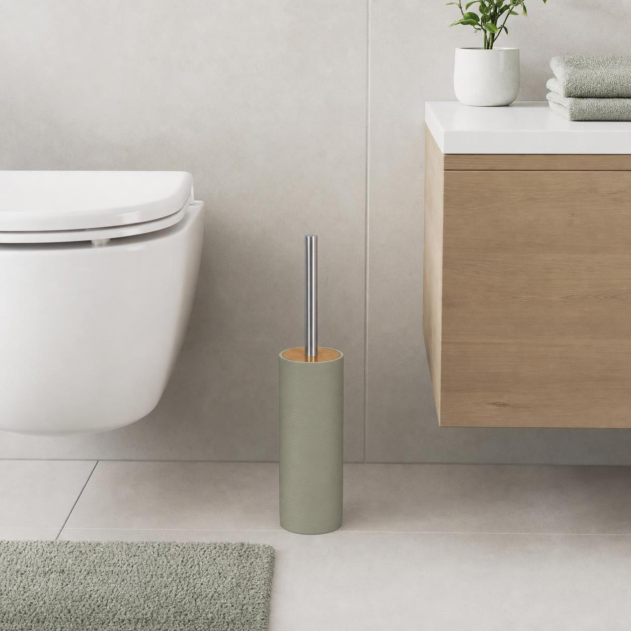 Eine grüne WC-Bürstengarnitur steht neben Toilette und Waschtisch.