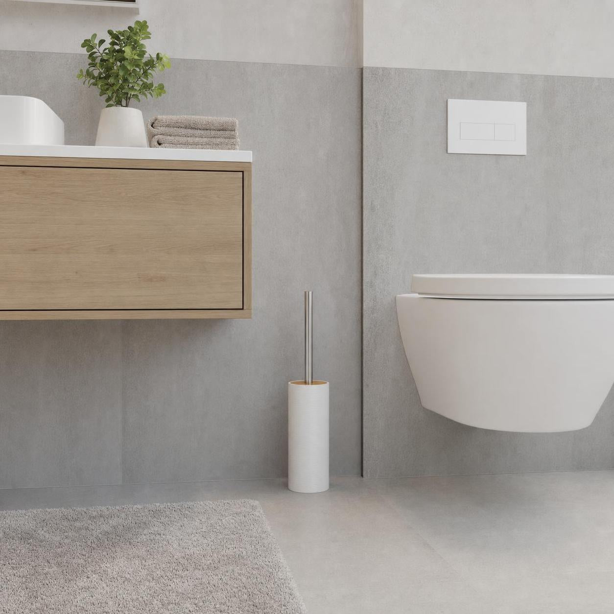 Weiße WC-Bürste im Halter steht neben einer Toilette im Bad.