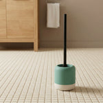 Türkis-weiße WC-Bürste mit Halter auf hell gefliestem Badezimmerboden