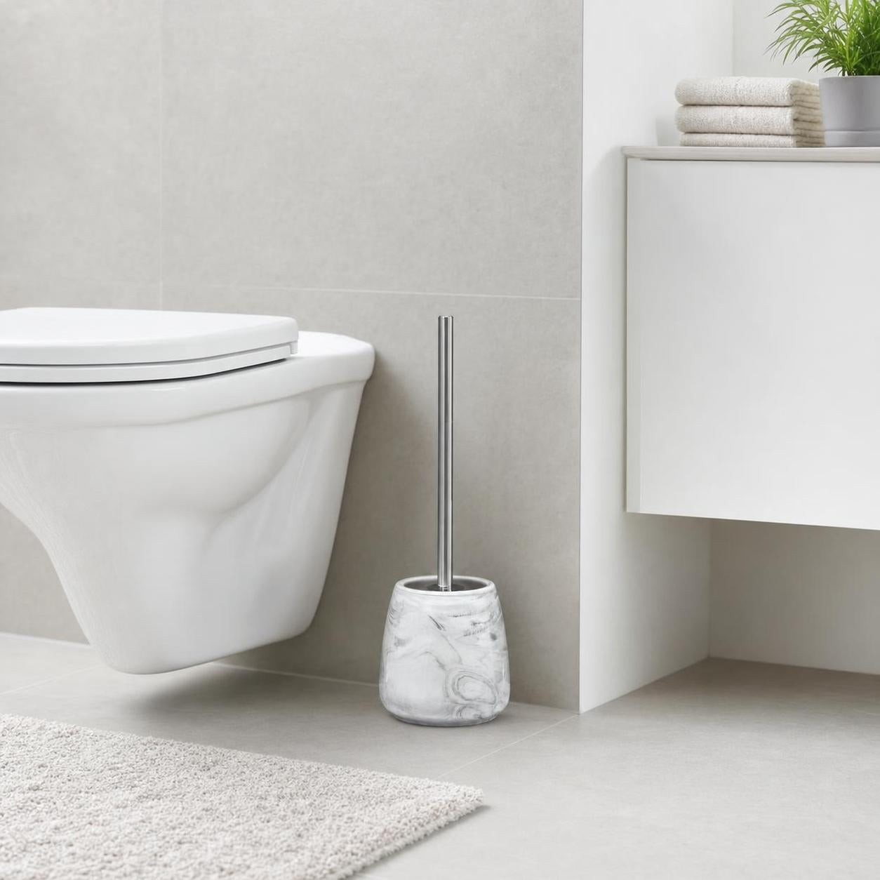 Eine WC-Bürste im Marmorhalter steht neben der Toilette im Bad.