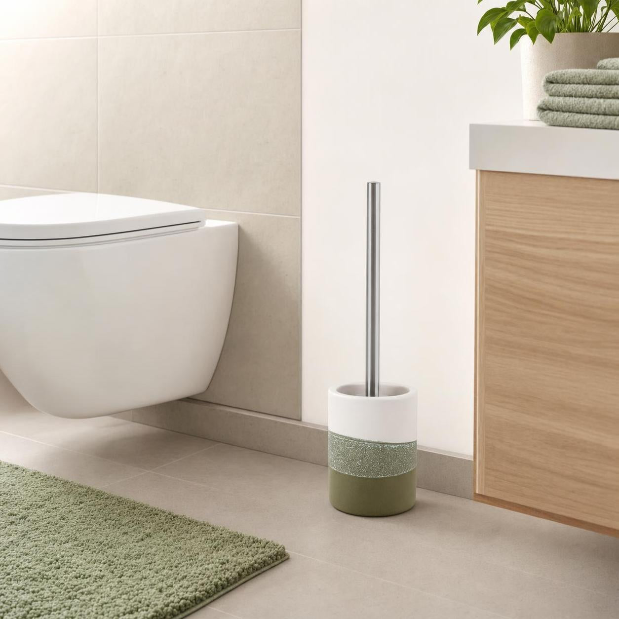 Eine grün-weiße WC-Bürste steht neben der Toilette im Bad.
