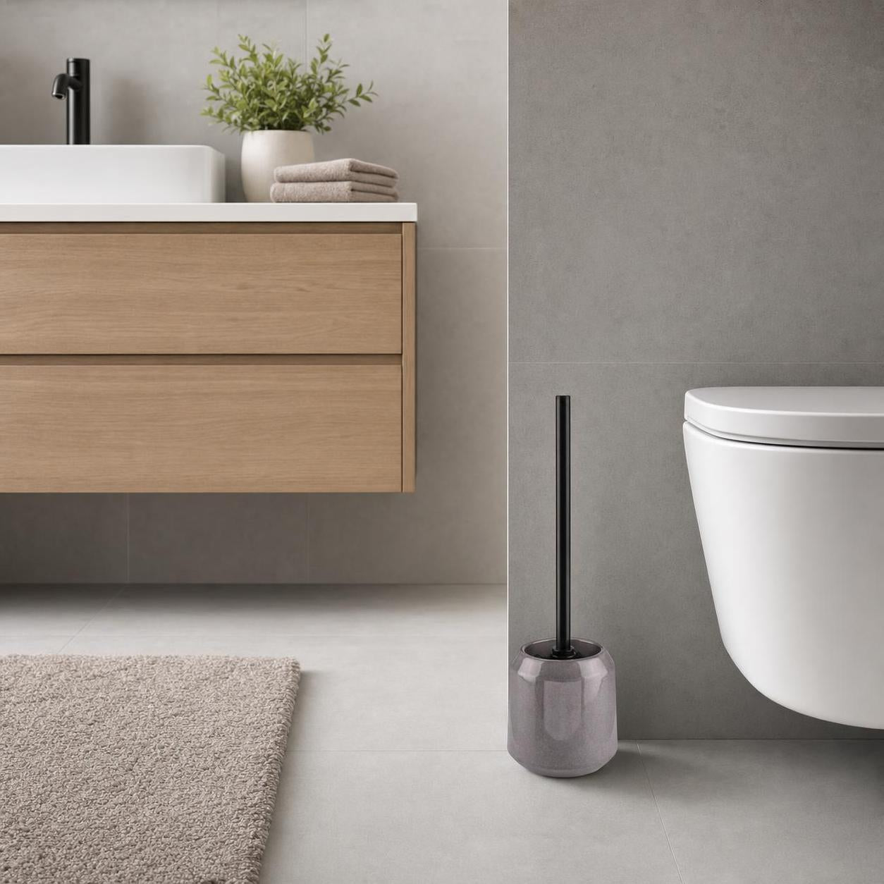 Grauer WC-Bürstenhalter mit schwarzer Bürste steht neben der Toilette.