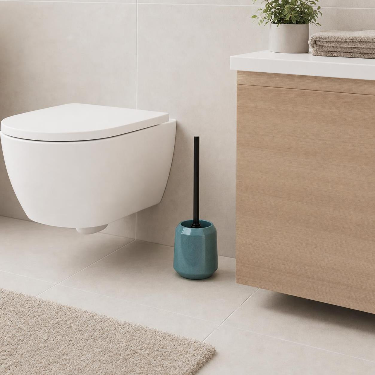 Eine türkisfarbene WC-Bürste steht neben der Toilette im modernen Bad.
