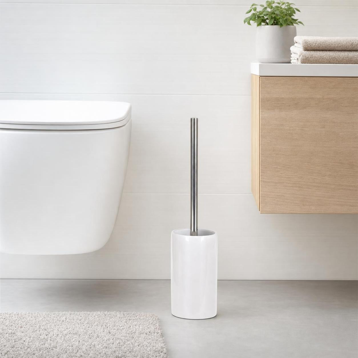 Weiße WC-Bürste mit Chromgriff steht neben Toilette und Badschrank.