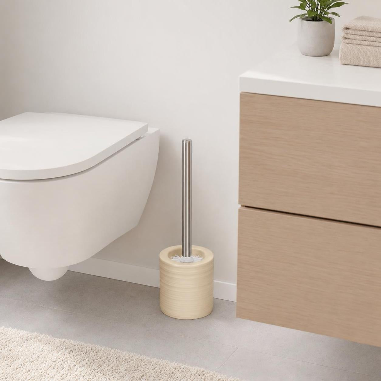 Eine WC-Bürste im beigen Halter steht neben der Toilette im Bad.