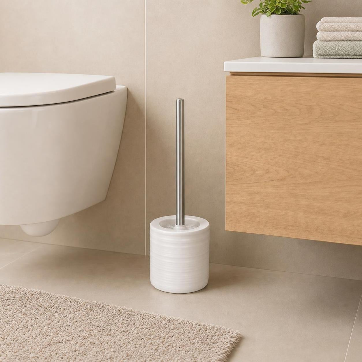 Eine weiße WC-Bürste steht neben Toilette und Holzwaschtisch.
