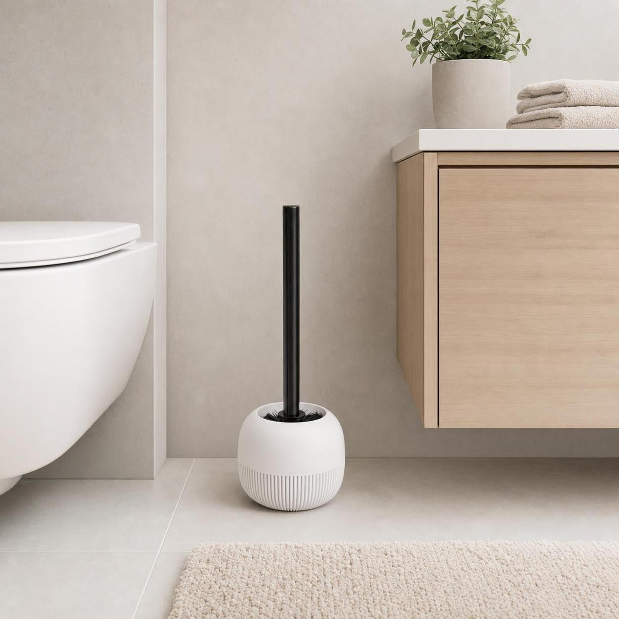 Weiße WC-Bürste mit schwarzem Griff steht neben Toilette und Waschtisch.