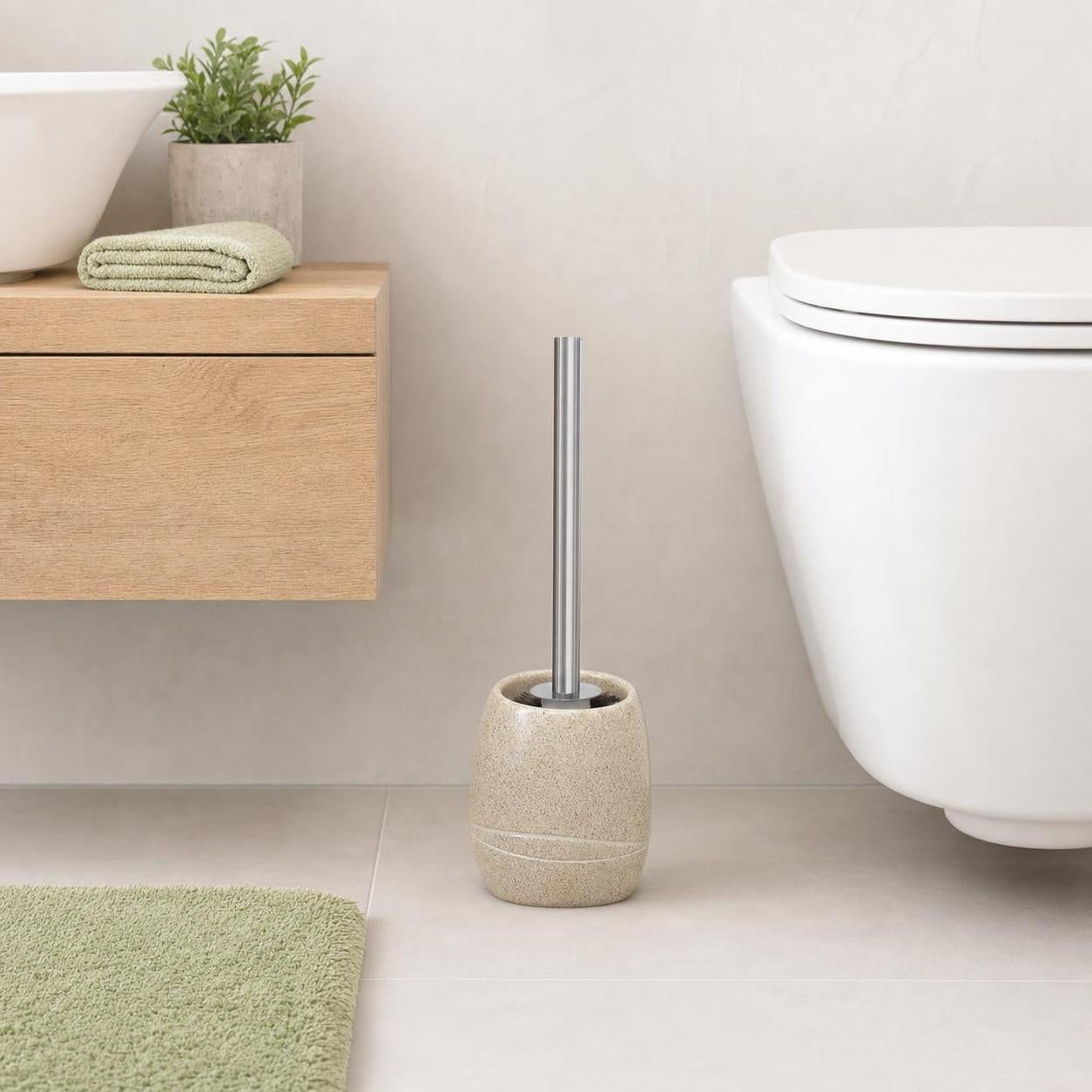 Eine Toilettenbürste mit beigem Halter steht neben dem WC im Bad.