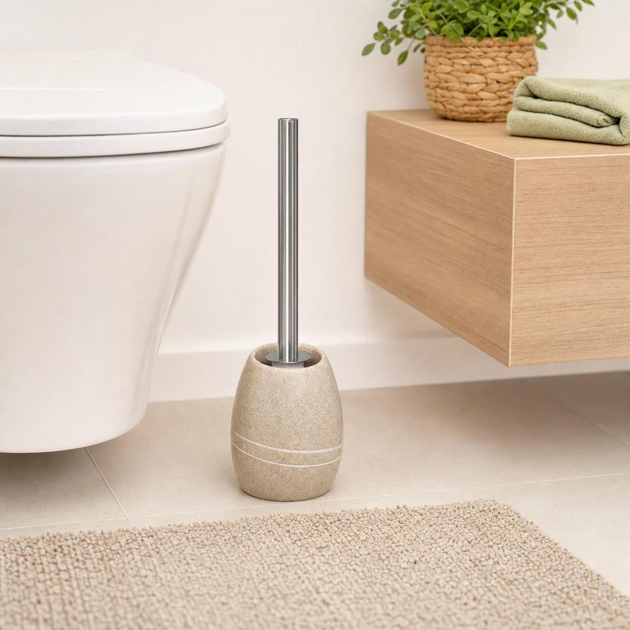 Eine Toilettenbürste mit beigem Halter steht neben der Toilette.