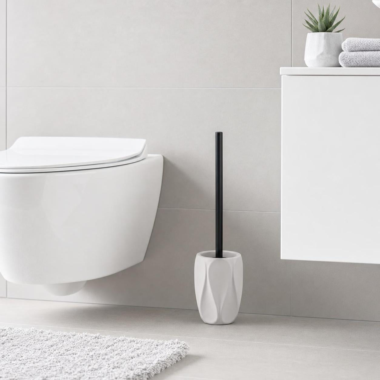 Weiße WC-Bürste mit schwarzem Stiel steht neben der Toilette.