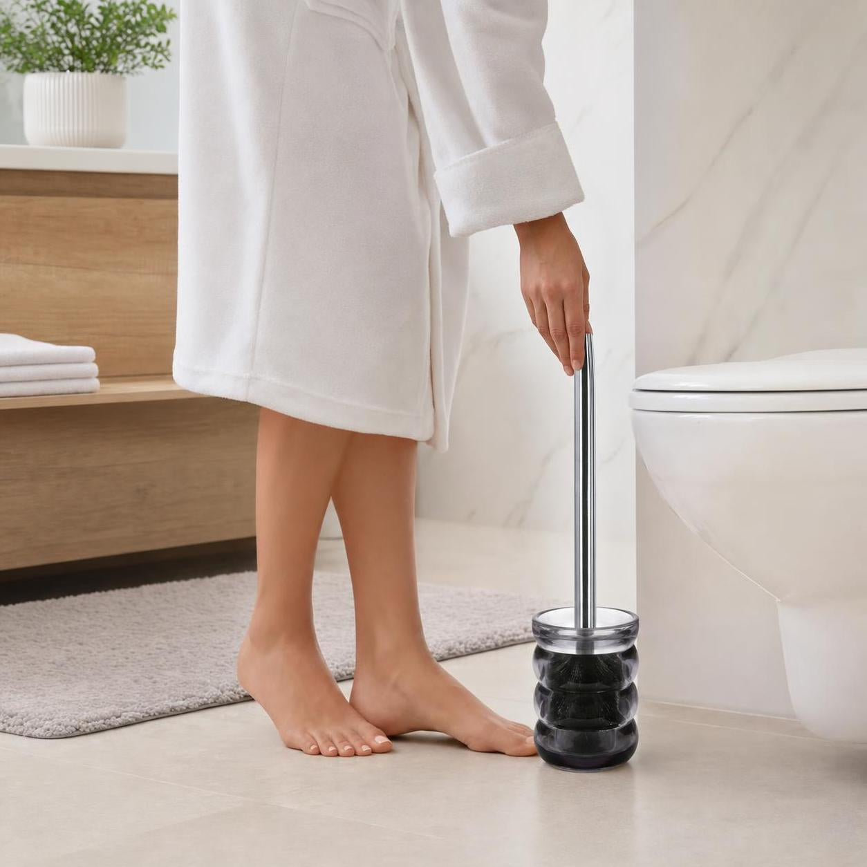 Eine WC-Bürste im schwarzen Halter steht neben der Toilette.