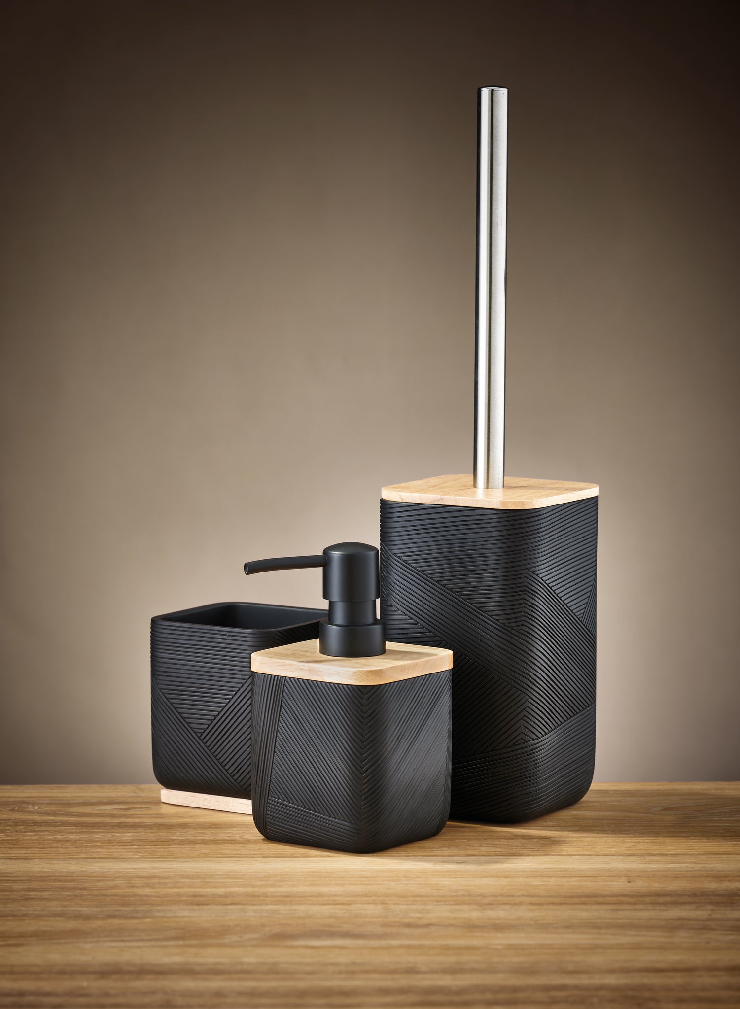 Schwarzer WC-Bürsten-Halter CROSSOVER mit passendem Spender und Becher auf Holzoberfläche.