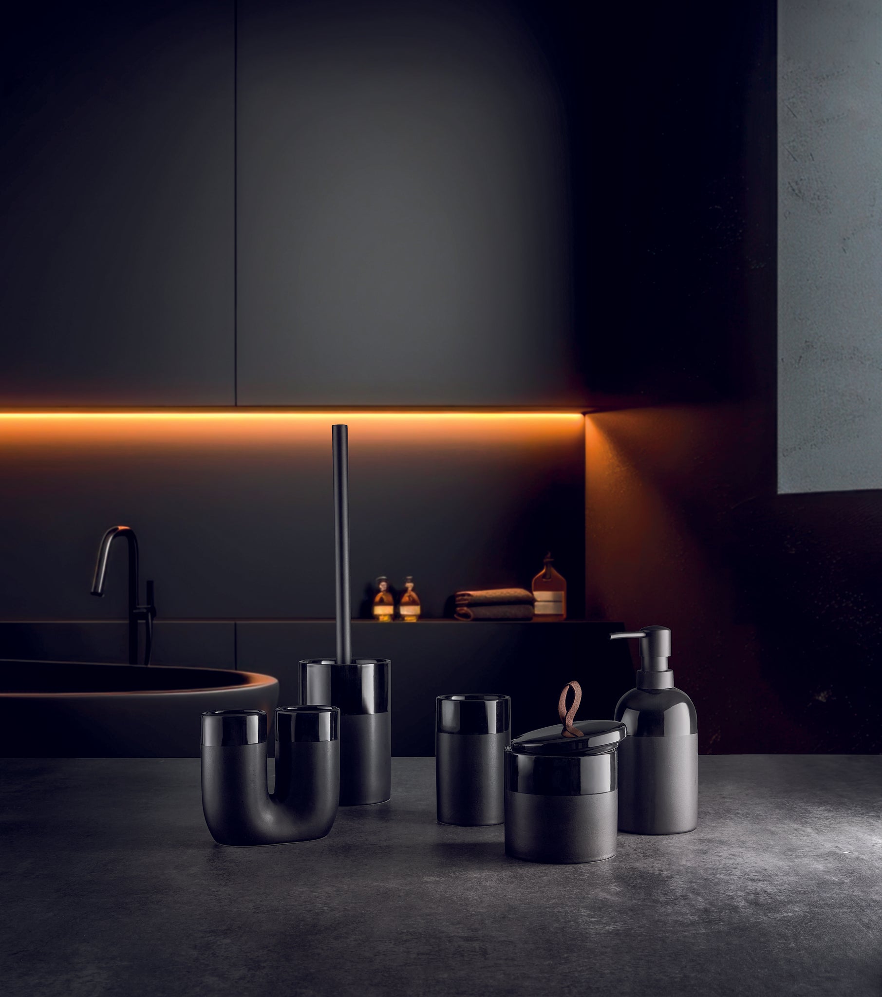 WC-Bürsten-Halter DEEP Schwarz steht mit weiteren Bad-Accessoires in dunklem Bad.