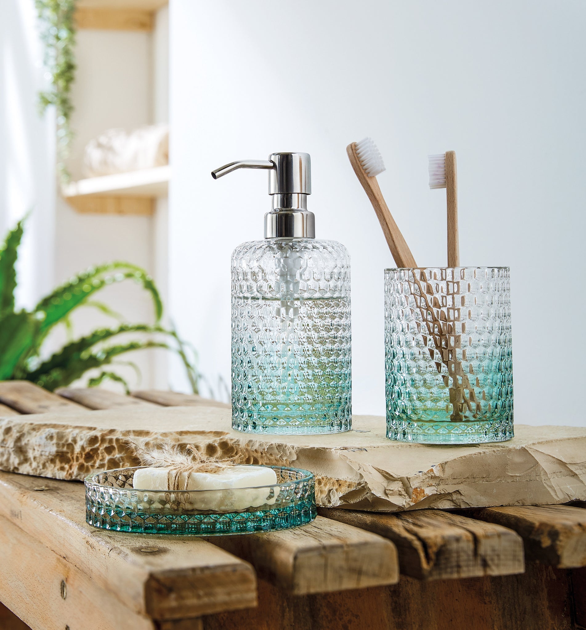 Badezimmer-Accessoires der Serie MELUA Maledivia aus strukturiertem Glas auf rustikalem Holztisch.