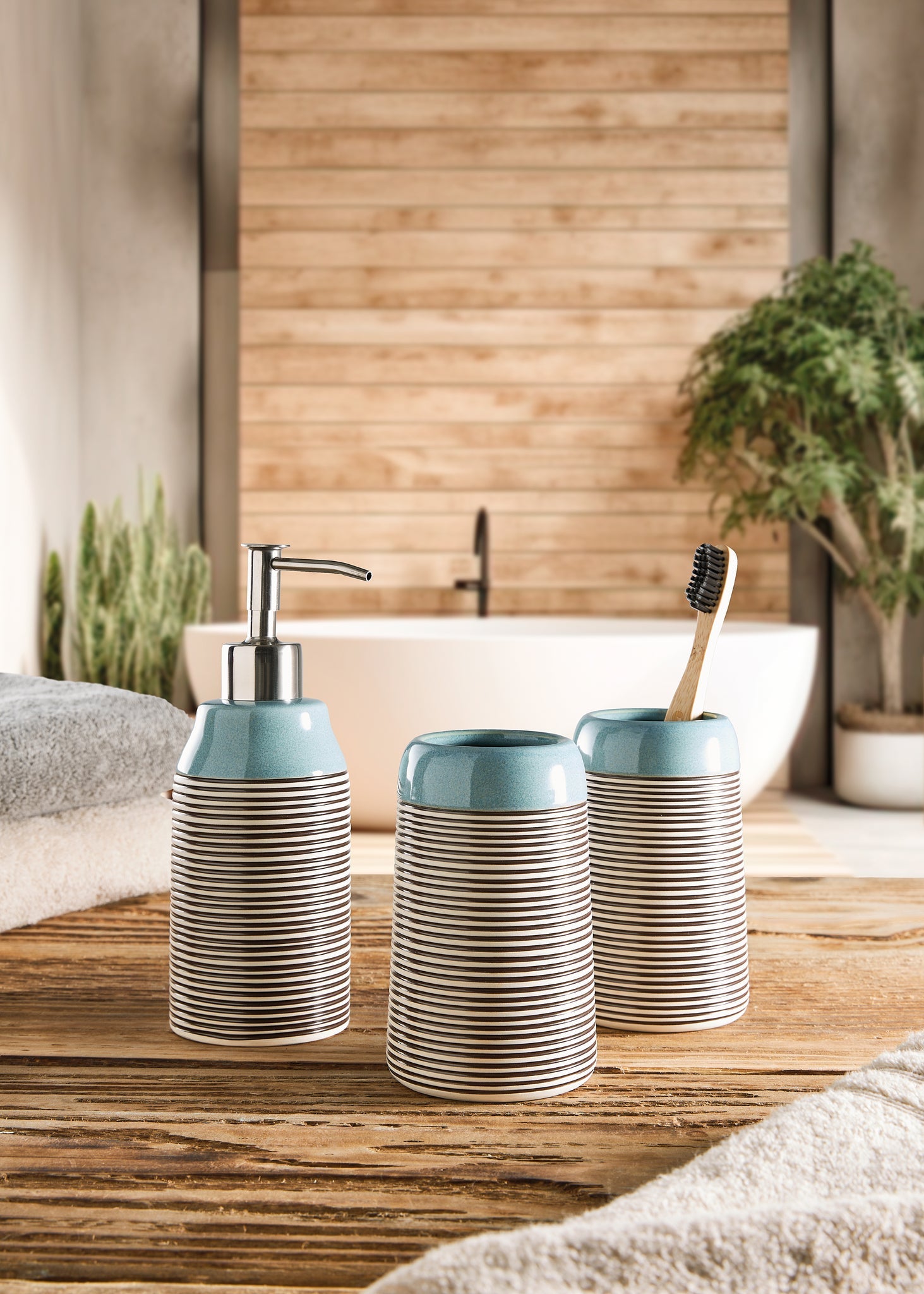 WC-Bürsten-Halter OKAPI Mauritius als Teil eines Badezimmer-Sets auf Holzablage vor Badewanne.