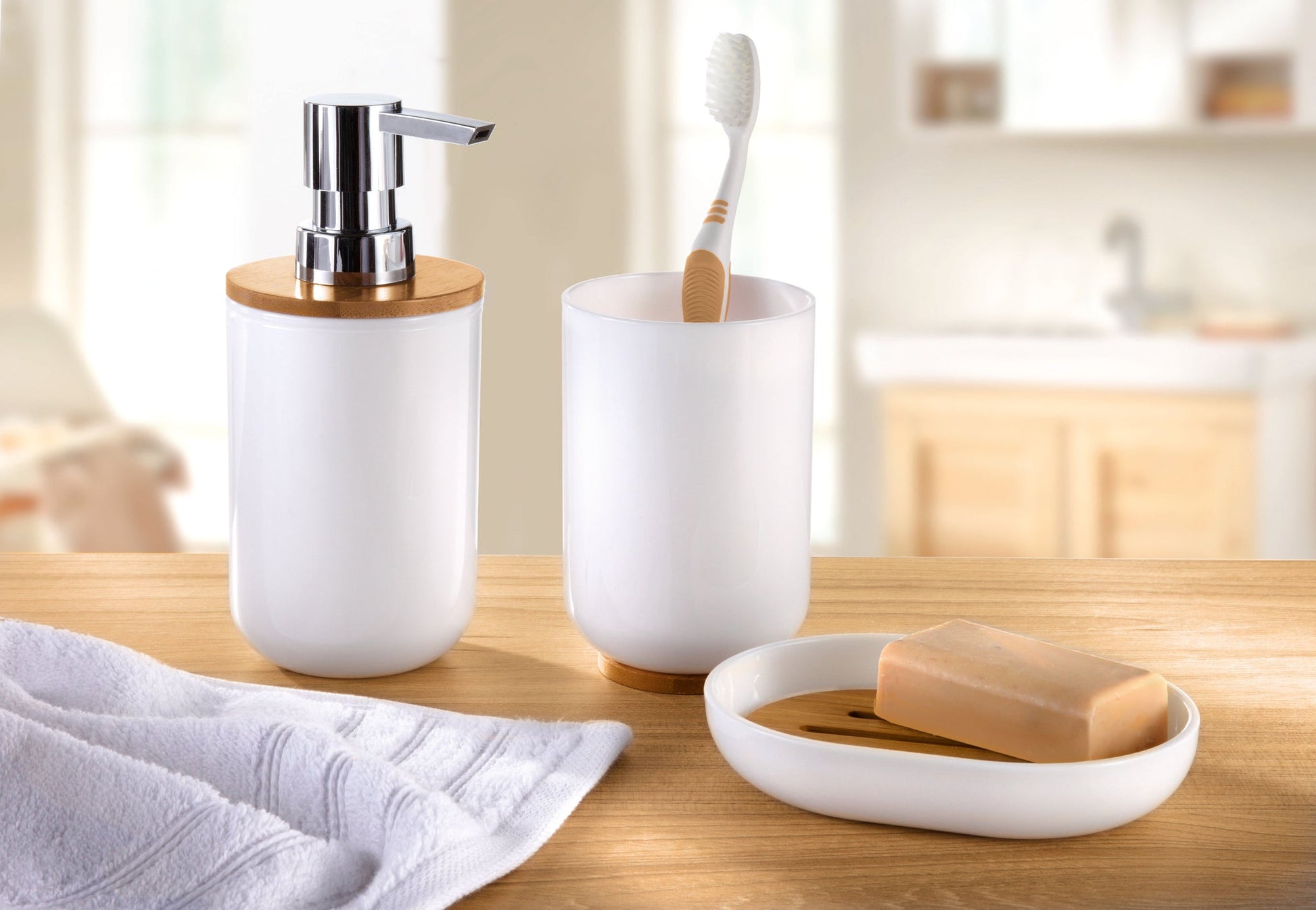 Weißes Bad-Set mit Spender, Becher, Seifenschale und Handtuch auf Holz