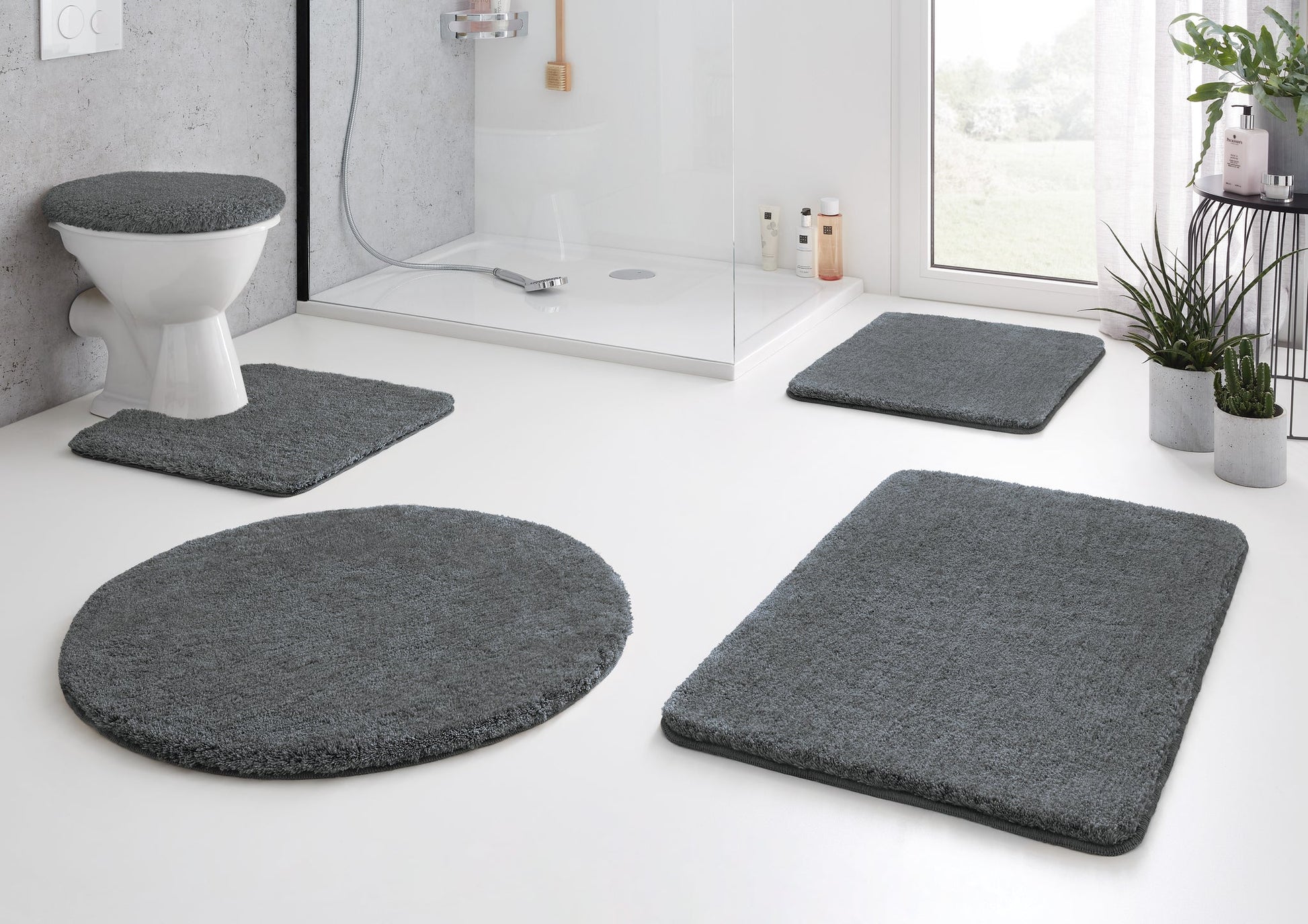 Graues fünfteiliges Badteppich-Set vor Dusche und WC im modernen Bad
