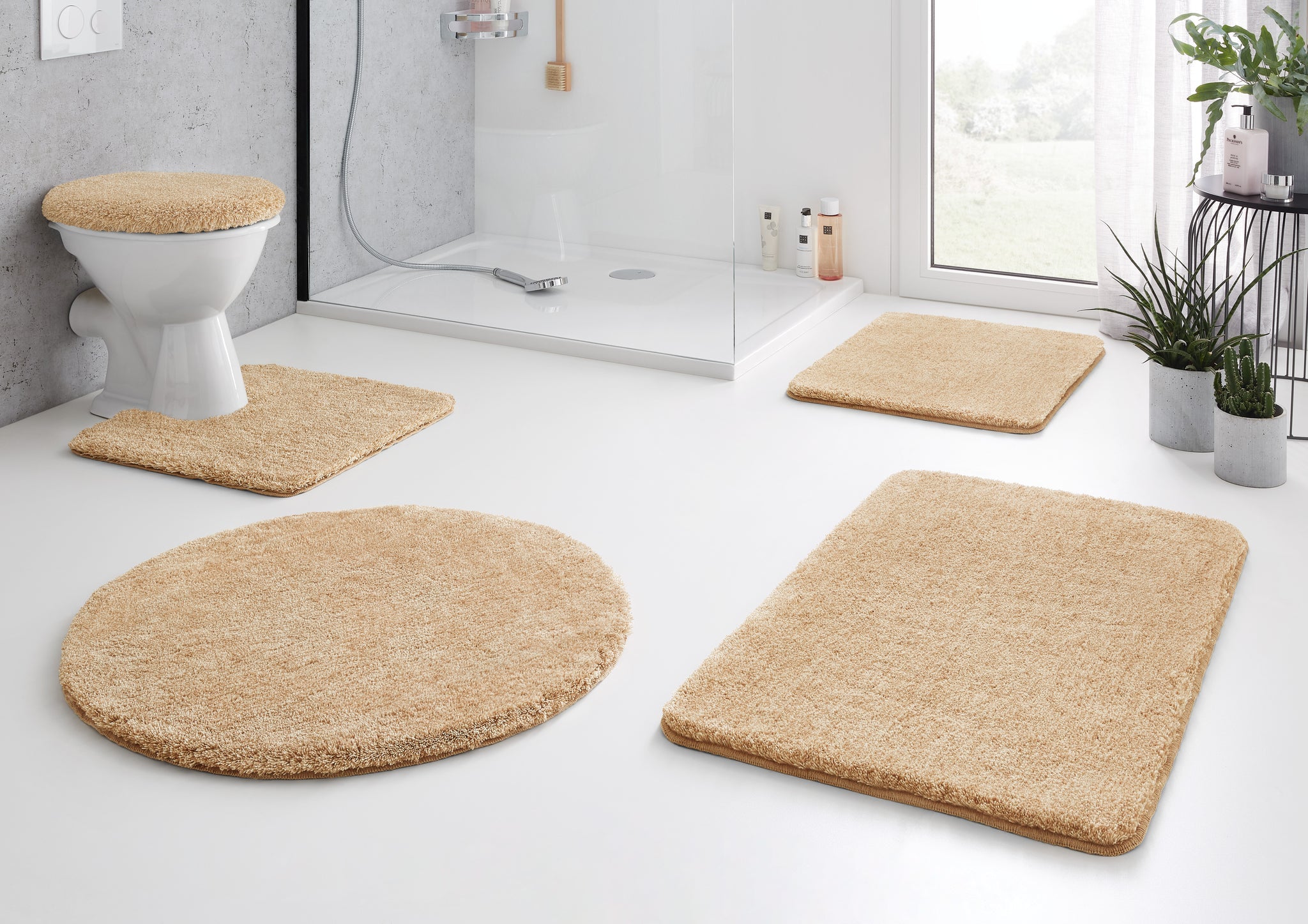 Beiges fünfteiliges Badematten-Set im modernen, hellen Badezimmer mit Dusche
