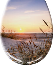 Sonnenuntergang über Sanddünen mit Dünengras am ruhigen Meereshorizont