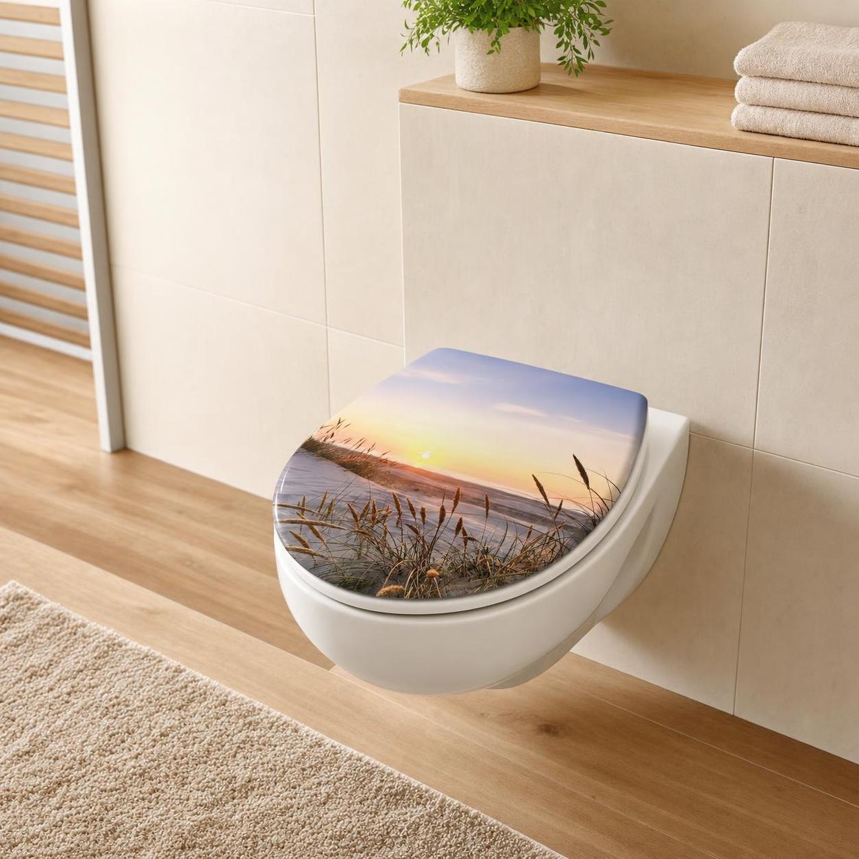 Ein WC-Sitz mit Strandmotiv bei Sonnenuntergang im hellen Bad.