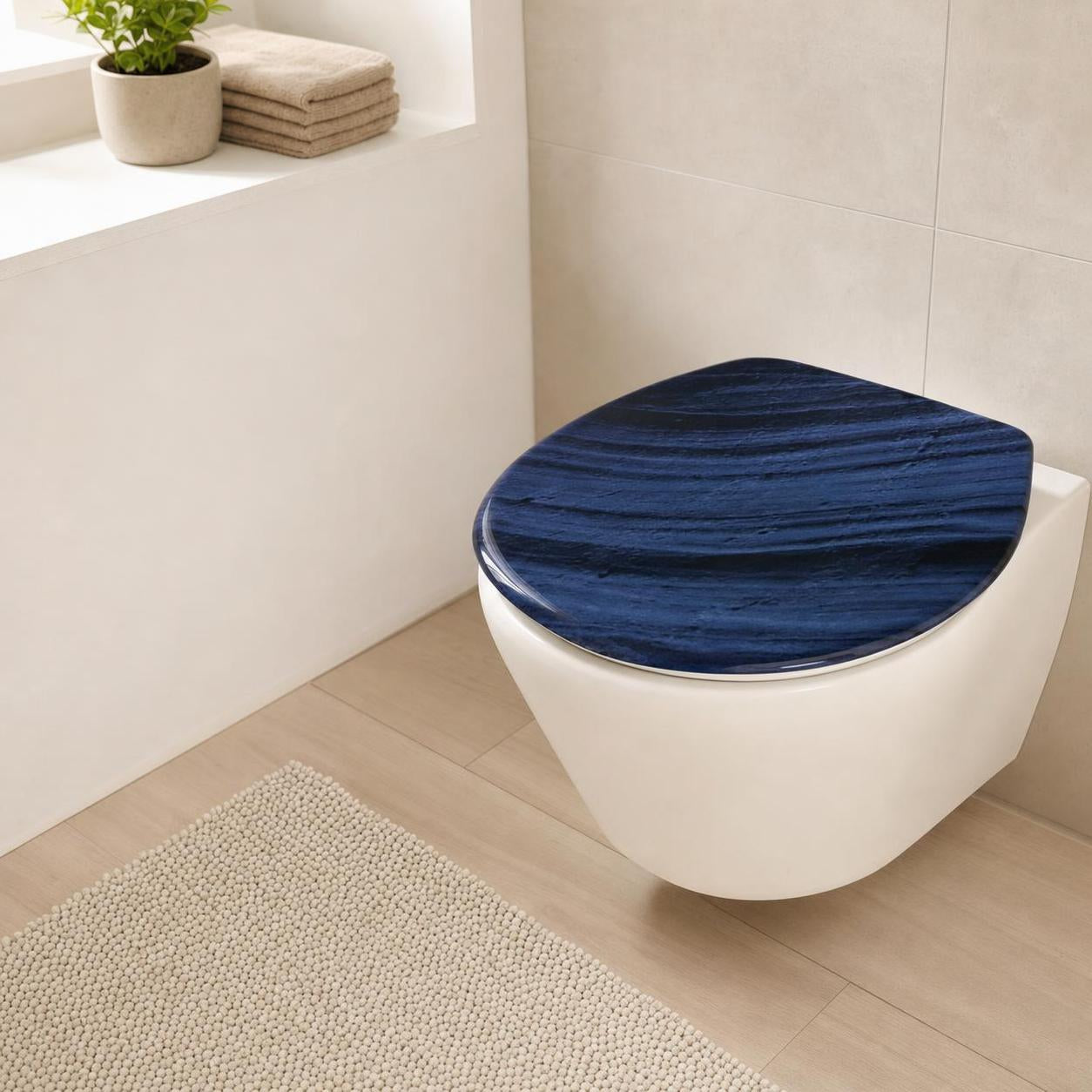 Ein blauer WC-Sitz mit Holzmaserung liegt auf einer weißen Toilette.